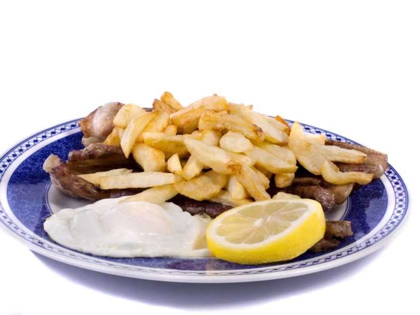 Viande de bœuf ou de porc frite, servie avec un œuf au plat, pommes de terre frites, riz et un mixte de salade verte, tomates et oigno